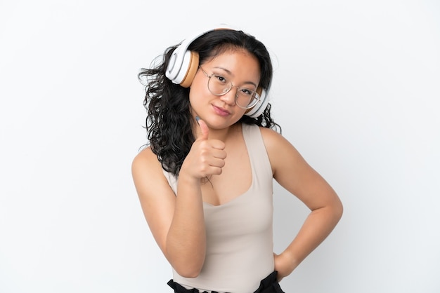 Jonge Aziatische vrouw geïsoleerd op een witte achtergrond luisteren muziek en met duim omhoog