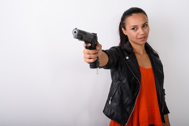 jonge Aziatische vrouw gericht pistool op afstand klaar om te schieten tegen witte ruimte