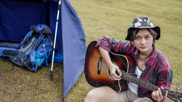 Jonge Aziatische vrouw gitaarspelen op camping