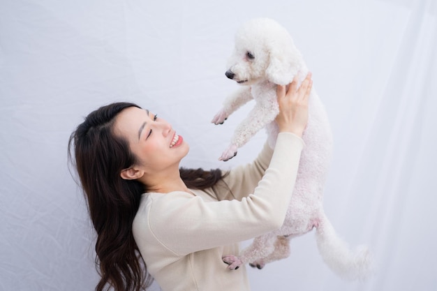 Jonge aziatische vrouw haar hond knuffelen op witte achtergrond