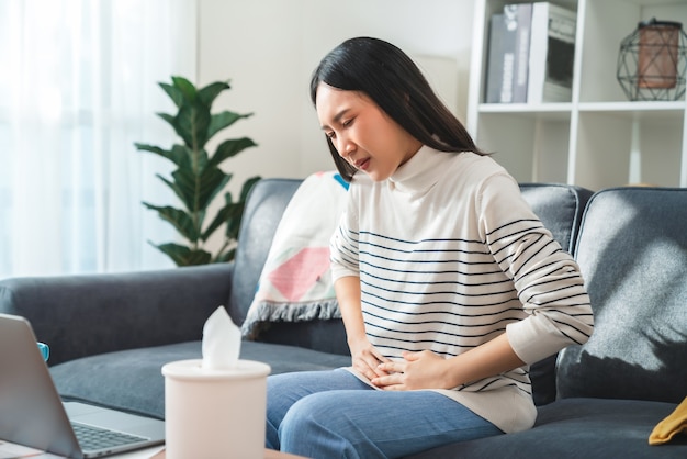 Jonge Aziatische vrouw handen houden de maag en pijn periode krampen vast omdat ze menstruatie hebben.