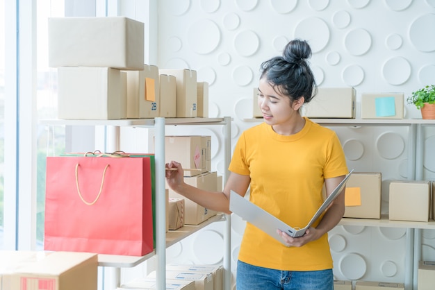 Jonge aziatische vrouw het controleren van goederen op voorraad plank magazijn