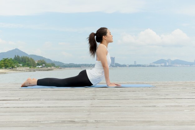 Jonge Aziatische vrouw het praktizeren yoga bij kust