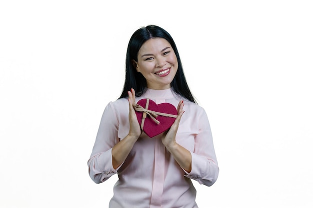 Jonge aziatische vrouw houdt een hartvormige geschenkdoos in beide handen Valentijnsdag of jubileumcadeau geïsoleerd op een witte achtergrond