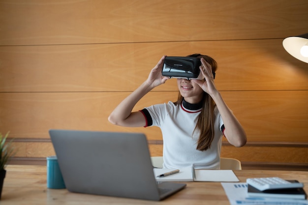 Jonge aziatische vrouw in vr-bril die virtueel werkt voor financieel thuis