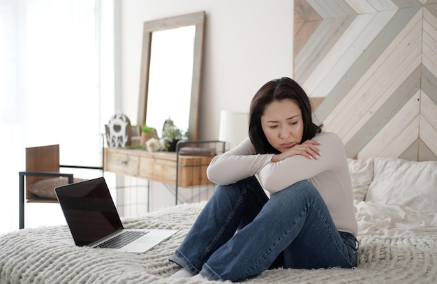 Foto jonge aziatische vrouw leest slecht nieuws op laptop ziet er wanhopig uit, voelt zich gestrest belangrijk gegevensverlies bericht formulier bank over schuld overstuur gebruiker klant die laptop gebruikt, voelt zich gefrustreerd gek over computerprobleem