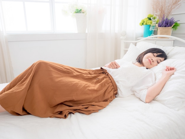 Jonge Aziatische vrouw liggend in bed thuis in de slaapkamer.