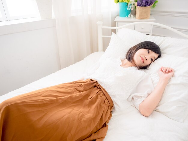 Jonge Aziatische vrouw liggend in bed thuis in de slaapkamer.