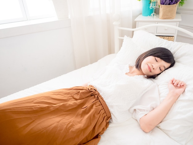 Jonge Aziatische vrouw liggend in bed thuis in de slaapkamer.