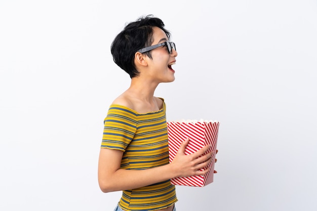 Jonge Aziatische vrouw met 3d glazen en holding een grote emmer popcorns