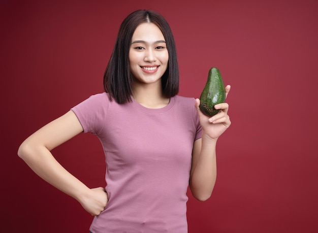 Jonge Aziatische vrouw met avocado-fruit op de achtergrond