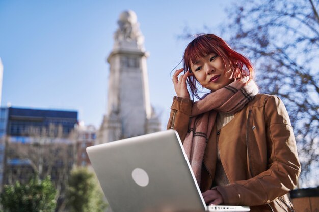 Jonge Aziatische vrouw met behulp van haar laptopcomputer in de stad