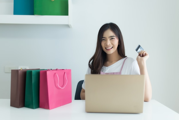 Jonge Aziatische vrouw met behulp van laptopcomputer en creditcard bedrijf. Online winkelen en browsi