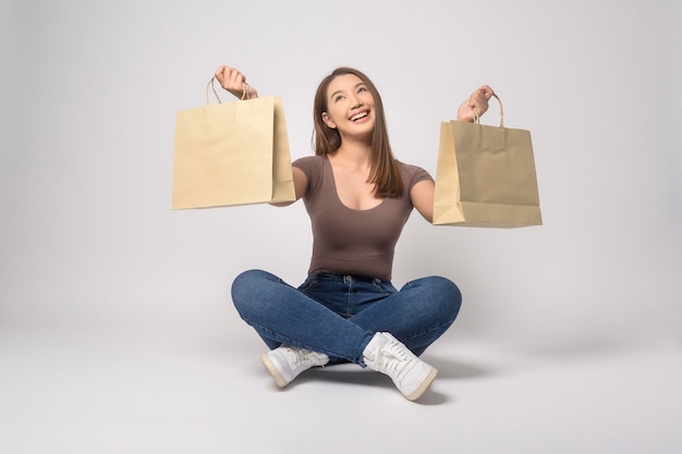 Jonge aziatische vrouw met boodschappentas over witte achtergrond studio winkelen en financiën concept