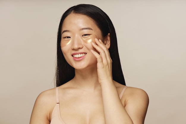 Jonge Aziatische vrouw met collageen oogvlekken.