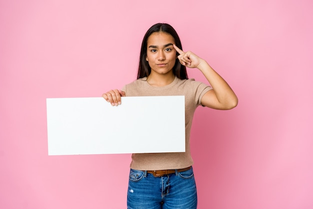 Jonge Aziatische vrouw met een blanco papier voor wit iets wijzende tempel met vinger, denken, gericht op een taak.