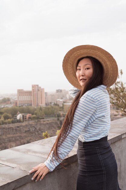Jonge Aziatische vrouw met hoed reizen en wandelen in de stad op zonnige zomerdag