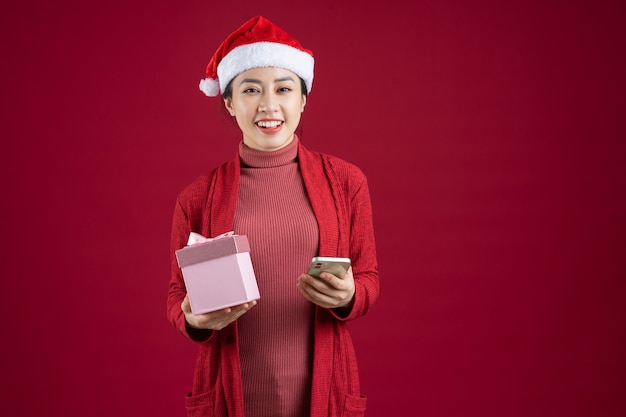 Jonge Aziatische vrouw met kerstmuts op rode achtergrond