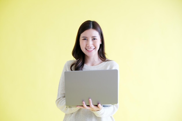 Jonge Aziatische vrouw met laptopcomputer glimlachend en camera kijkend