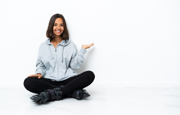 Jonge Aziatische vrouw met rolschaatsen op de vloer die handen uitstrekt naar de zijkant om uit te nodigen om te komen