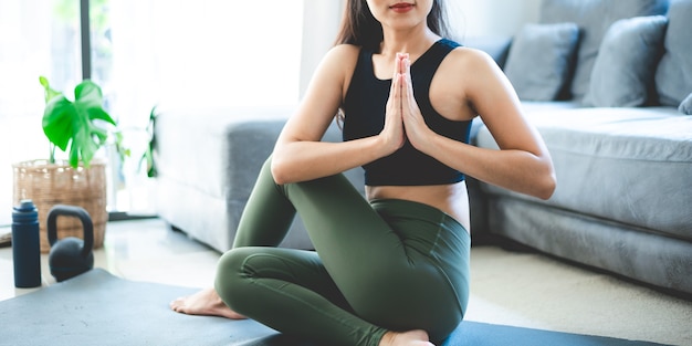 Jonge Aziatische vrouw oefent door yoga thuis sportschool, gezonde vrouwelijke levensstijl met fitness sport training thuis, meisje doet lichaam actieve lichaamsbeweging binnen huis kamer, ontspanning en wellness