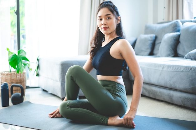 Jonge Aziatische vrouw oefent door yoga thuis sportschool, gezonde vrouwelijke levensstijl met fitness sport training thuis, meisje doet lichaam actieve lichaamsbeweging binnen huis kamer, ontspanning en wellness