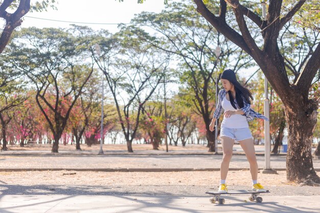 Jonge Aziatische vrouw old-school skateboard rijden langs stoep