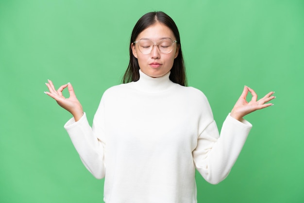 Jonge Aziatische vrouw over geïsoleerde achtergrond die een teken van stiltegebaar toont dat vinger in mond zet