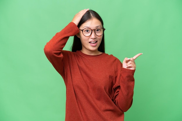 Jonge Aziatische vrouw over geïsoleerde achtergrond met gekruiste armen en vooruit kijkend