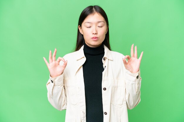 Jonge Aziatische vrouw over geïsoleerde chroma key achtergrond in zen pose