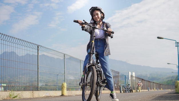 Jonge Aziatische vrouw pauzeert de fiets voordat ze naar het werk gaat