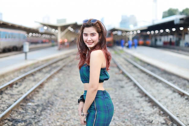 jonge Aziatische vrouw permanent en pose in treinstation met glimlachen en schoonheid gezicht