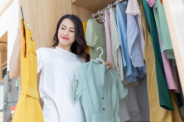 Jonge Aziatische vrouw probeert kleren aanxA