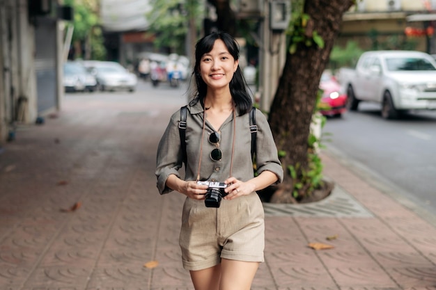Jonge Aziatische vrouw rugzak reiziger met behulp van digitale compact camera genieten van straat culturele lokale plek en glimlach