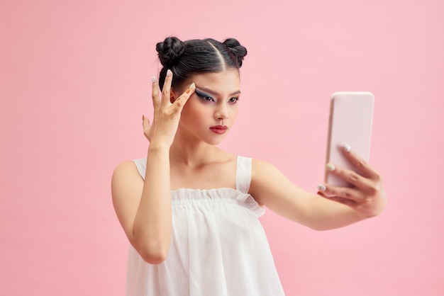 Jonge Aziatische vrouw selfie met mobiele telefoon op roze achtergrond