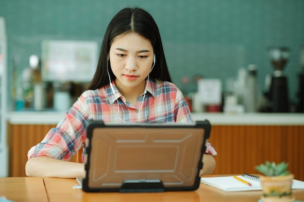 Jonge aziatische vrouw studeert achter de laptop en gebruikt een koptelefoon bij offsitexa