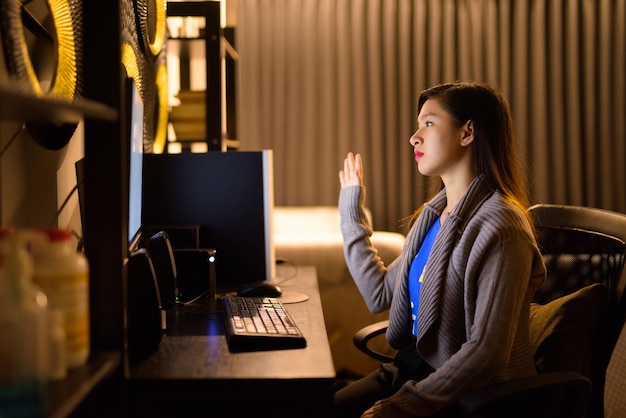 Jonge Aziatische vrouw videobellen tijdens het werken vanuit huis