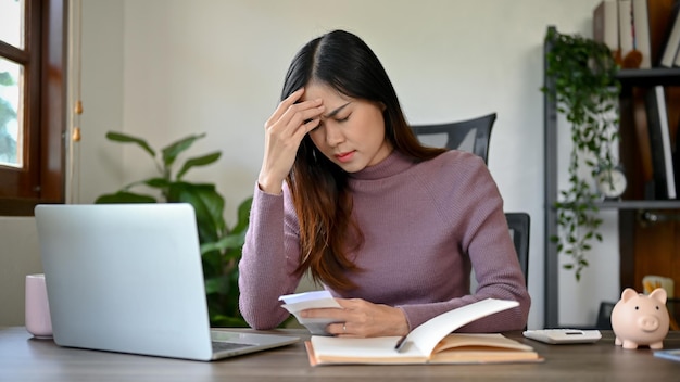 Jonge Aziatische vrouw voelt zich overstuur en gestrest na het kijken naar de rekeningen betalen rekeningen of belastingen