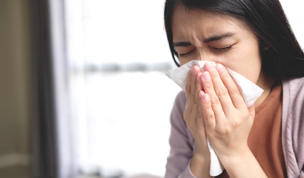 Jonge Aziatische vrouwen bedekken hun mond en neus met tissues tijdens griep, hoesten en niezen om verspreiding van het virus te voorkomen