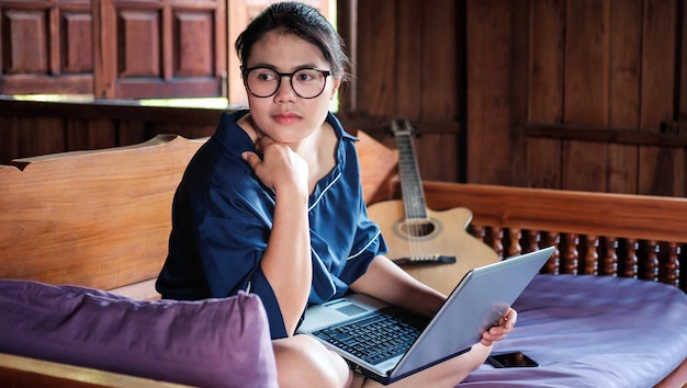 Jonge Aziatische vrouwen of vrouwenzaken Werken Zit thuis met een notebookcomputer op een houten tafel