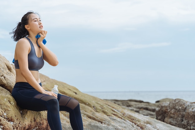 Foto jonge aziatische vrouwenagent die na training rusten die op het strand lopen