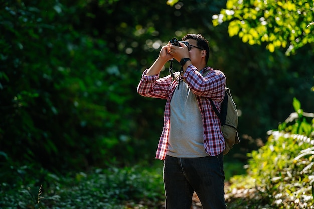 Jonge Aziatische wandelaar en rugzak gebruiken camera om foto's te maken in de kopieerruimte van het bos