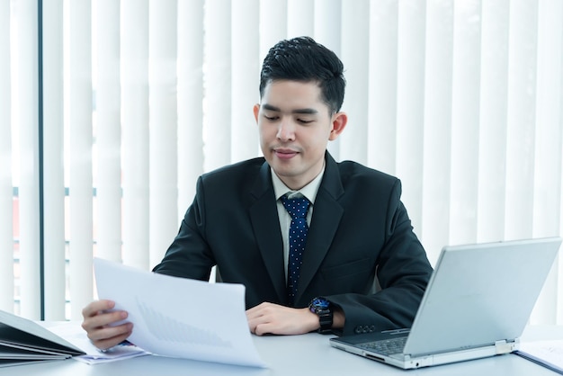 Jonge Aziatische werknemer aan het werk op laptop tijdens werkdag in office Zakenman blij met glimlach in de officethailand mensen bij bedrijf