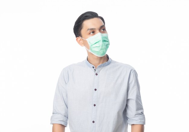 Jonge Aziatische zakenman die een hygiënisch masker draagt en omhoog kijkt om infectie, 2019-nCoV of coronavirus te voorkomen.