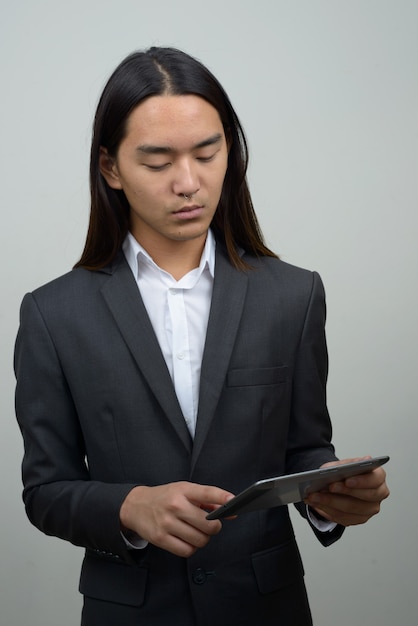 Jonge Aziatische zakenman met lang haar met behulp van digitale tablet