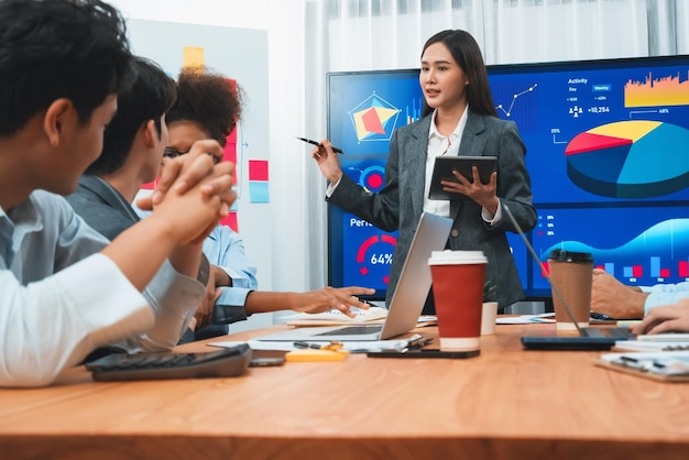 Jonge Aziatische zakenvrouw die data-analysedashboard op tv-scherm presenteert in moderne vergadering Zakelijke presentatie met een groep zakenmensen in vergaderruimte Concord