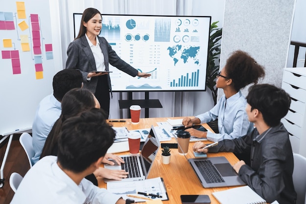 Jonge Aziatische zakenvrouw die data-analysedashboard op tv-scherm presenteert in moderne vergadering Zakelijke presentatie met een groep zakenmensen in vergaderruimte Concord