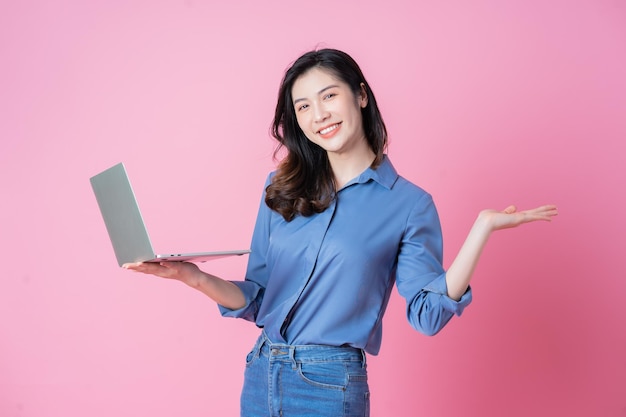 Jonge Aziatische zakenvrouw met behulp van laptop op roze achtergrond