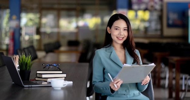Jonge Aziatische zakenvrouw mooie charmante lachende vergadering werken op kantoor. Camera kijken.
