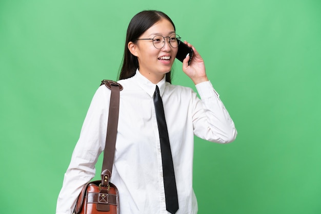 Jonge aziatische zakenvrouw over geïsoleerde achtergrond die een gesprek voert met de mobiele telefoon